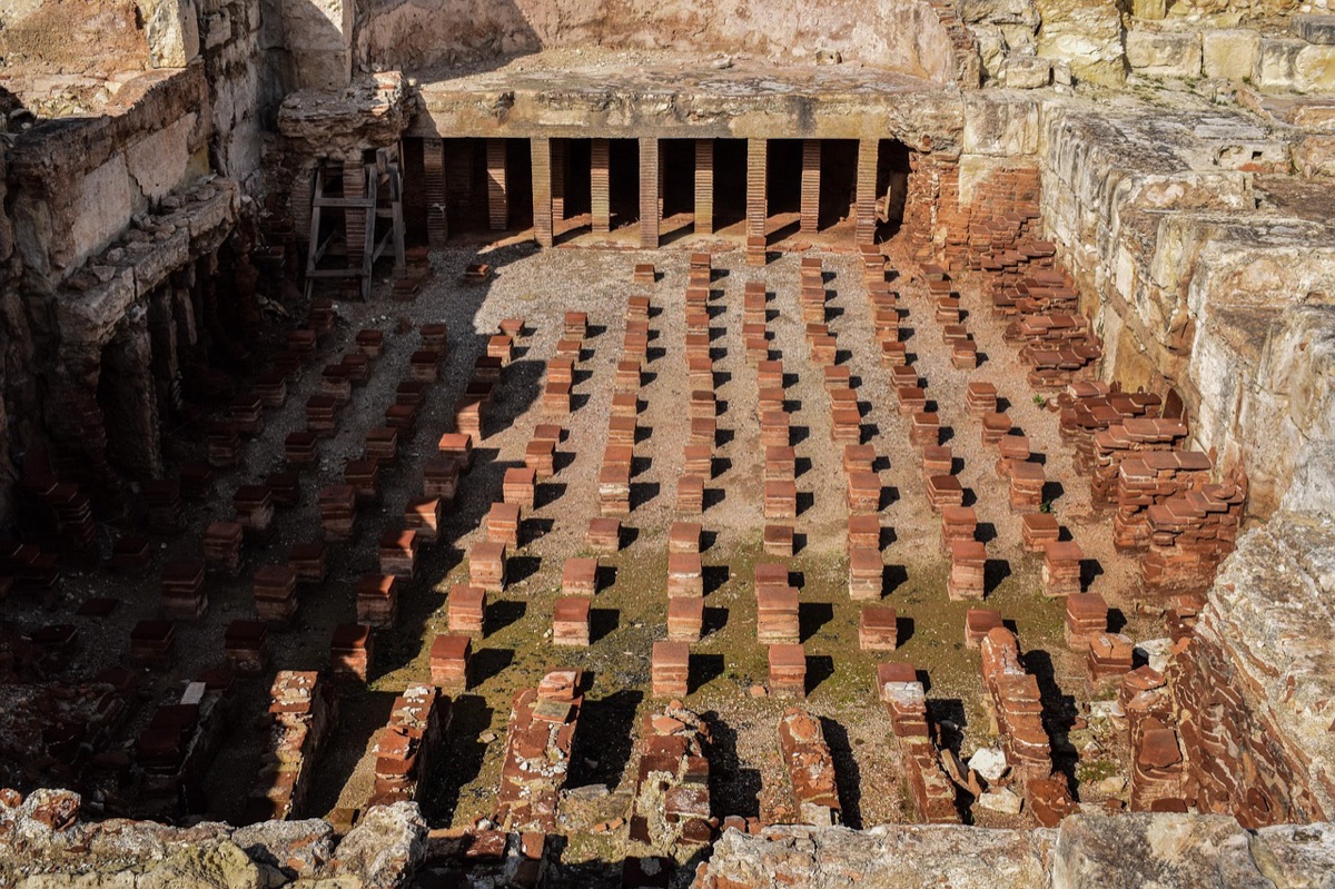 Un gruppo di turisti in mezzo alle ruine romane, con luce naturale e un'atmosfera moody.